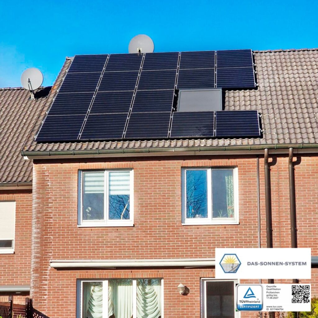 Mehrfamilienhaus mit Solarpaneelen auf dem Dach vor blauem Himmel.
