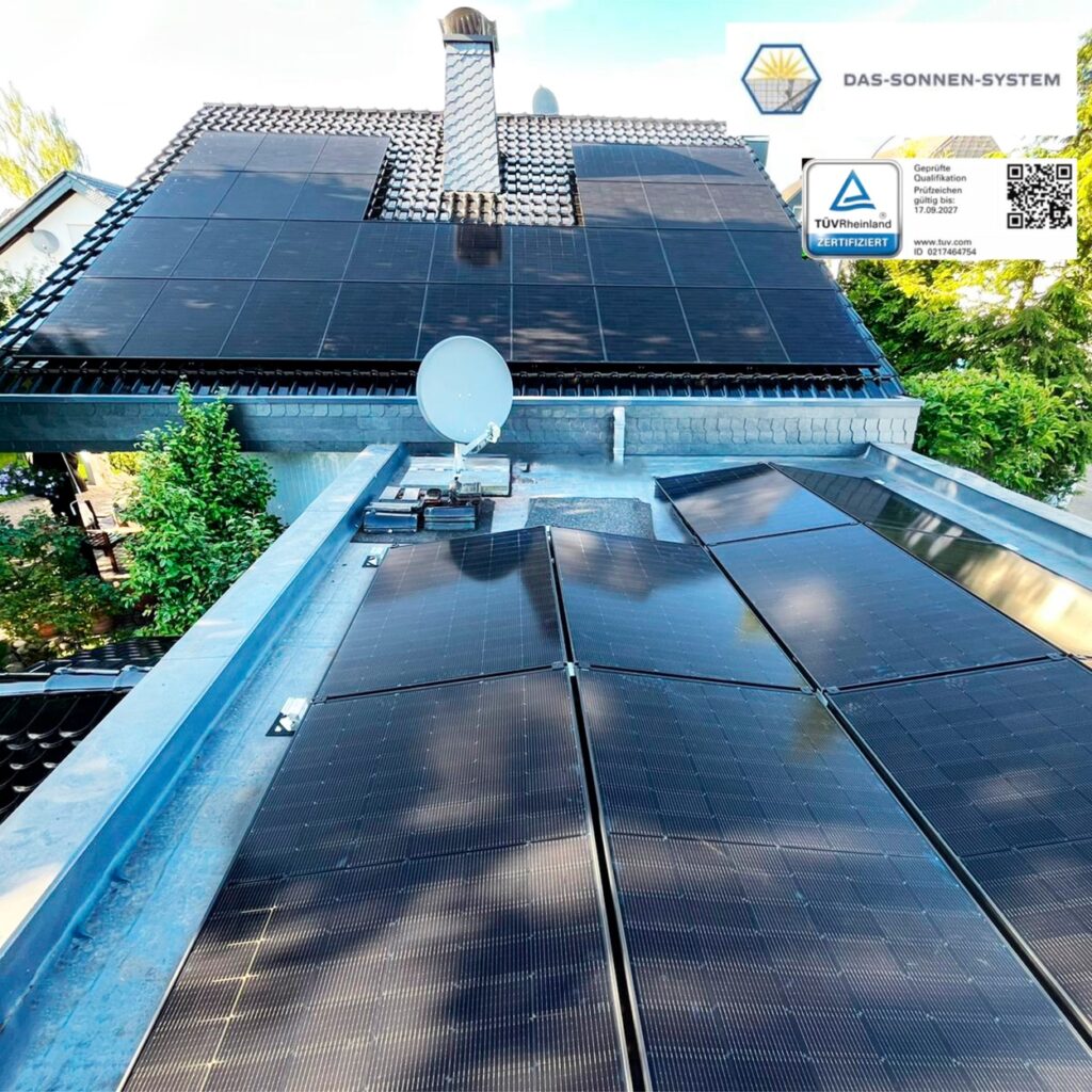 Solarmodule auf einem Hausdach bei sonnigem Wetter mit Kamin und Satellitenschüssel.